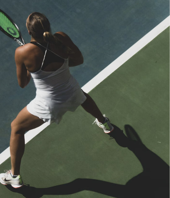 Tennis player mid-serve on a hard court, seen from above